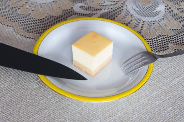 Bıçak ve çatal ile beyaz plaka üzerinde Cheesecake.