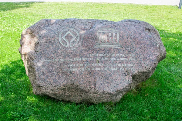 Malbork, Polonia - 18 de junio de 2017: Piedra con infromación sobre el Castillo de la Orden Teutónica en Malbork, Polonia. Castillo de Malbork es el castillo más grande del mundo medido por la superficie terrestre . — Foto de Stock