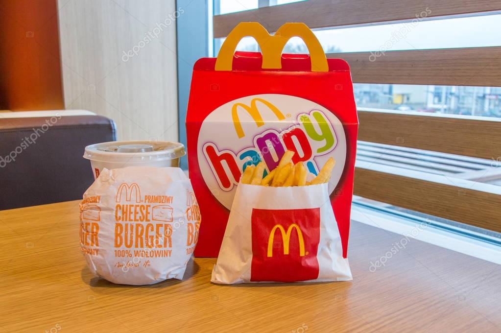 Gdansk, Poland - February 21, 2018: Mcdonalds happy meal box with Coca-Cola, french fries and cheeseburger on wooden table.