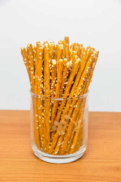 Sesame sticks in glass on wooden table.