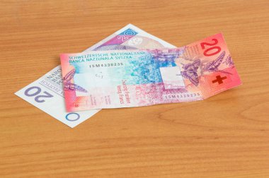 20 PIN ve 20 Chf banknotları ahşap masada..