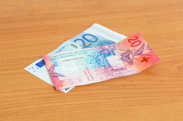 20 Eur och 20 Chf sedlar på träbord. — Stockfoto