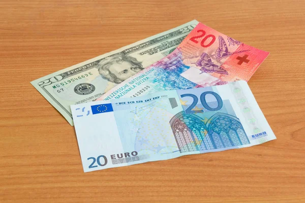 20 Usd, 20 Chf i 20 Eur banknotów na drewnianym stole. — Zdjęcie stockowe