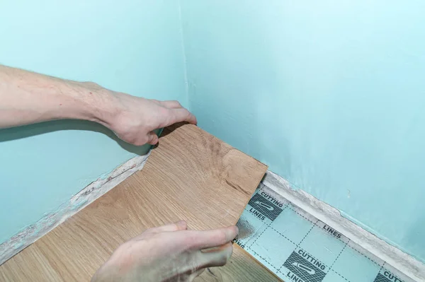 The man arranges the last row of floor panels in the room. — Stock Photo, Image