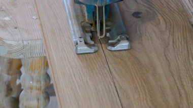 Elektrikli bir yapboz kullanarak zemin paneli kesiliyor.