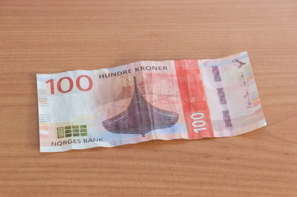 100 Norwegian krone banknote (NOK) on wooden table.