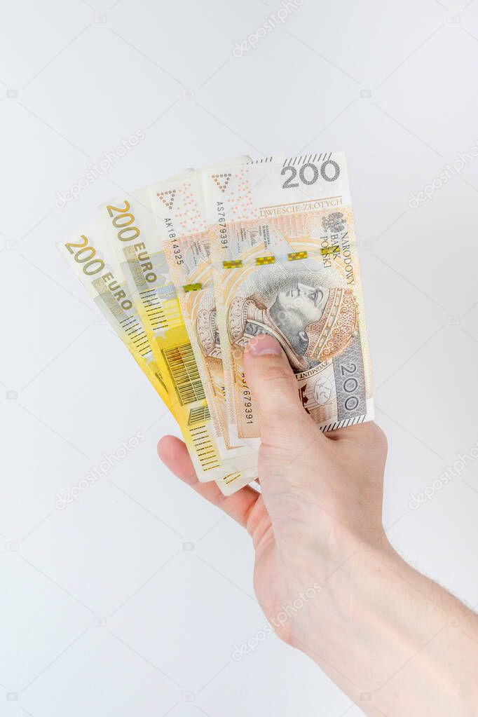 200 EUR and 200 PLN banknotes held in right hand.