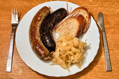 Lezzetli czech geleneksel jitrnice, sosis, ve jelita, kanlı sosisler, doğranmış lahana ve ekmek ile ahşap masa üzerinde çatal ve bıçak üst görüşlü ekmek
