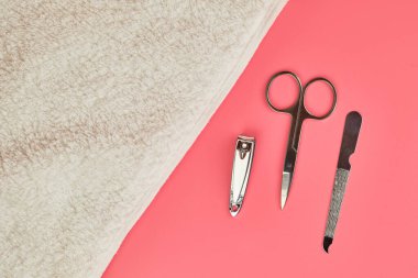 Pembe arka planda beyaz havluyla manikür araçları