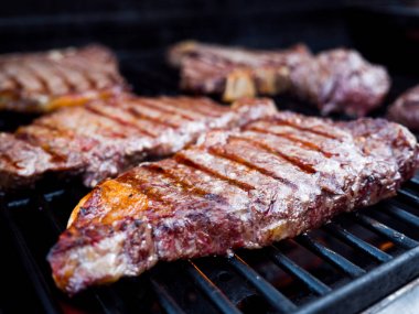 Yakın çekim fotoğraf Dana fileto mignon ve t-bone biftek bir arka bahçe Barbekü için bir gaz ateş ızgarada dahil olmak üzere çeşitli kesim.