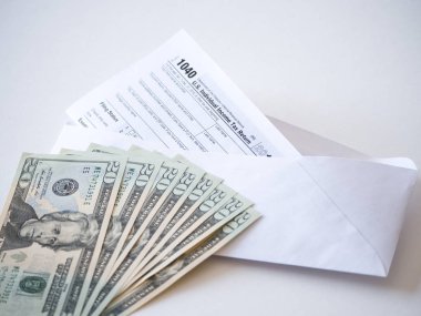 Fotoğraf 20 dolar faturaları yığını ve vergi indirimi tasarruf temsil eden bir posta zarf ile hazine bireysel gelir vergisi beyannamesi formunun 1040 federal bölümünün kapatın.