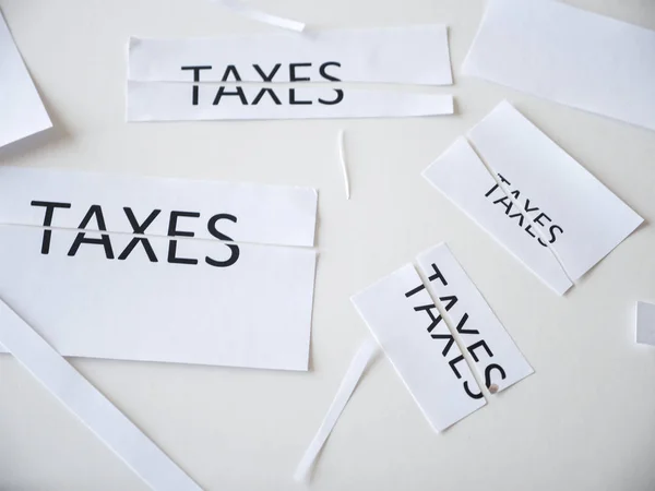 Pieces of paper and scraps of paper with some cut in half with the word taxes written on it representing tax cuts at federal and state governments saving Americans money with increased deductions.