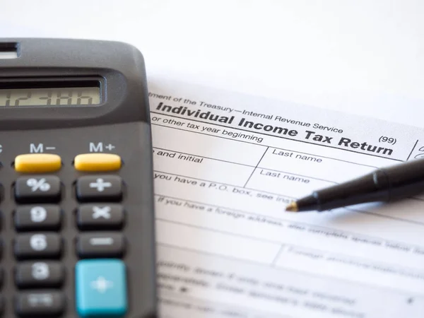 Close up photograph of individual income federal tax return paperwork with calculator and black ballpoint pen at borders for a nice tax season background, backdrop or wallpaper image.