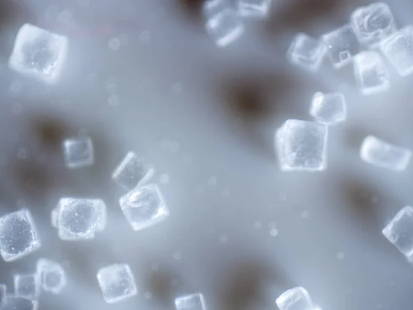 An extreme closeup macro microscopic image of a pile of clear cubed salt crystals showing the intricate detailing of the common cooking ingredient, preservative, and flavoring.