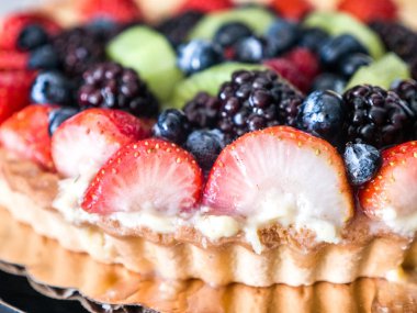 Portre fotoğrafı bir güzel ve renkli canlı meyve tatlı yaban mersini, çilek, kivi ve böğürtlen meyve tepesi ile tart ve bir mutfak tezgah üstü ayarla yivli kabuk kenar usanmış.