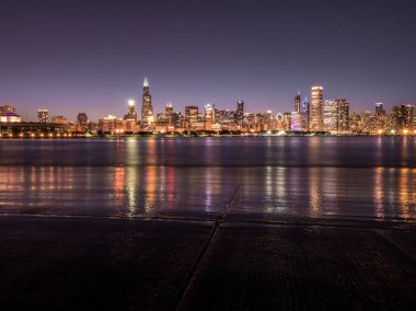 Güzel uzun pozlama Chicago gece manzarası fotoğraf renkli kırmızı, yeşil, mor, mavi, pembe, turuncu ve sarı ışık ve su yansımalar Michigan Gölü ve kıyı ön planda bina ile