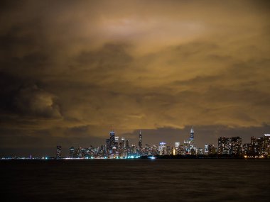 Sadece güneş battıktan sonra uzun pozlama fotoğraf ön plan ve yukarıda bulutlu gökyüzü Michigan Gölü ile Chicago şehir manzarası binalarda renkli ışıkların güzel gece zaman.