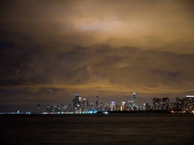 Sadece güneş battıktan sonra uzun pozlama fotoğraf ön plan ve yukarıda bulutlu gökyüzü Michigan Gölü ile Chicago şehir manzarası binalarda renkli ışıkların güzel gece zaman.