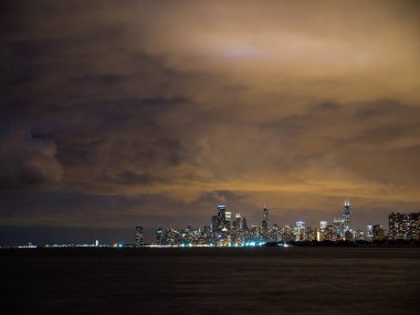 Sadece güneş battıktan sonra uzun pozlama fotoğraf ön plan ve yukarıda bulutlu gökyüzü Michigan Gölü ile Chicago şehir manzarası binalarda renkli ışıkların güzel gece zaman.