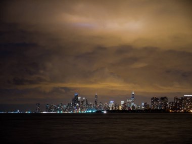 Sadece güneş battıktan sonra uzun pozlama fotoğraf ön plan ve yukarıda bulutlu gökyüzü Michigan Gölü ile Chicago şehir manzarası binalarda renkli ışıkların güzel gece zaman.