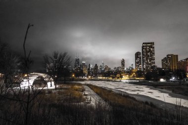 Chicago şehir manzarası Lincoln Park'ın Güney gölet kar ile gece hayvanat bahçesine bitişik yakın köprüden panoramik manzara görünümünü aşağıdaki yolları ve ön planda kısmen donmuş gölet kaplı.