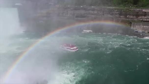 Niagara, NY - May 28th 2017: A tour boat from the Canadian side retreat from Horseshoe Falls on the Niagara river with rainbow overhead giving visitors an up close view of the world famous waterfall . — стоковое видео