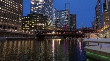 Trenler bir güzel kentsel sahne ya da zemin yaparak giderken Timelapse video olarak alacakaranlıkta Chicago Nehri'nin gece şehir ışık yansımaları ile çevredeki binalar ve manzarası ortaya.