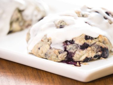 Ev yapımı yaban mersinli çörek hamur eritilmiş beyaz limon ve toz şeker sır tepsi ahşap tahıl masanın üzerine hizmet veren bir beyaz üzerine oturan fırın dışında taze yakın çekim.