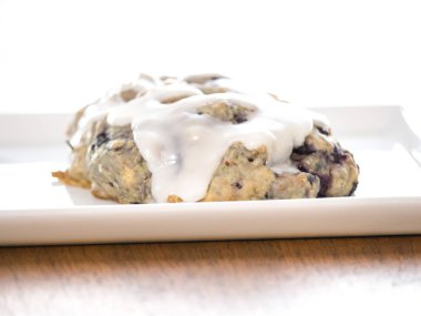 Ev yapımı yaban mersinli çörek hamur eritilmiş beyaz limon ve toz şeker sır tepsi ahşap tahıl masanın üzerine hizmet veren bir beyaz üzerine oturan fırın dışında taze yakın çekim.