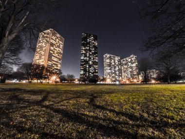 Güzel uzun pozlama gece fotoğraf yüksek doğmak konut kınamak bina ve Chicago yeşil çim ve çıplak kış ağaçları ile ışıklar ve gölgeler ön ve ötesinde bir karanlık gece gökyüzü