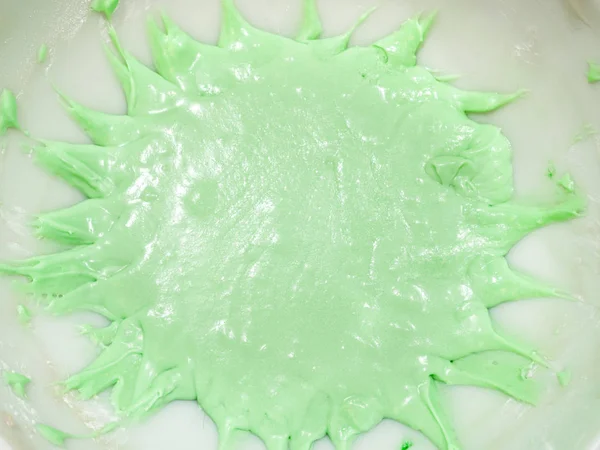 在厨房柜台顶部的白色陶瓷搅拌碗中 用尖飞溅状边缘的粉彩或薄荷绿色彩色结霜关闭视图 — 图库照片