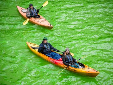 Chicago, IL - 17 Mart 2018: Kayak yapmak yollarını downtown Chicago şehir yıllık St Patrick's Day kutlamaları sırasında taze boyalı yeşil nehirde.