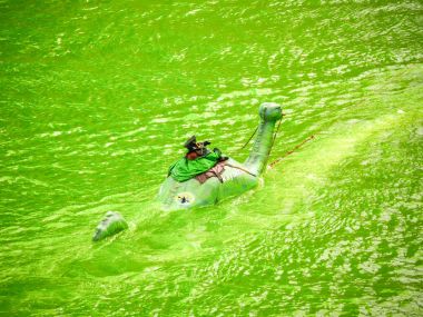 Chicago, IL - 17 Mart 2018: Kalabalıklar izle olarak yıllık St Patrick's Day kutlamaları için yeşil Nehri üzerinde bir tekne arkasında çekili bir el hazırlanmış loch ness canavarı bir masal cini gezintisi giyinmiş bir adam olarak.