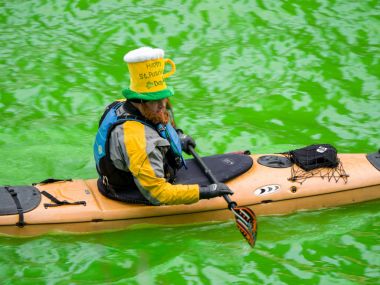 Chicago, IL - 17 Mart 2018: Kayak yapmak yollarını downtown Chicago şehir yıllık St Patrick's Day kutlamaları sırasında taze boyalı yeşil nehirde.