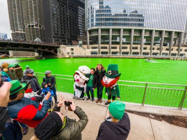 Chicago, IL - 17 Mart 2018: Kentin yıllık St Patrick's Day kutlama taze boyalı yeşil Chicago Nehri boyunca şehir merkezinde Cumartesi günü sırasında eğlenceli İrlandalı kostüm pozuyla insanlar rakamlar.