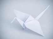 Krásné tradiční japonské origami jeřáb nebo orizuru vyrobené z bílé složený papír na bílém pozadí.