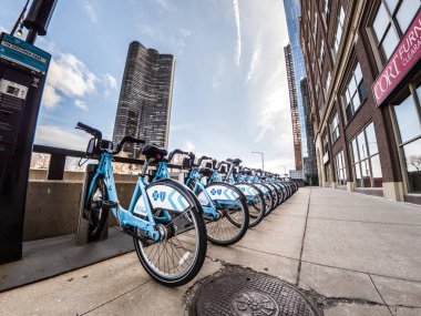 Chicago, IL - March 21st, 2018: Light blue Divvy bikes sit locked up in downtown Chicago along Lake Shore Drive. clipart