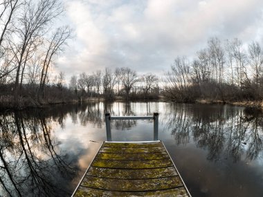 Yıpranmış ahşap ve Çelik İskele Wisconsin'de bir havuza günbatımında renkli bulutlar ve fantastik bir arka plan yapma ağaçlar yansıtan su ile dışarı taşıyorsa güzel manzara fotoğrafı.