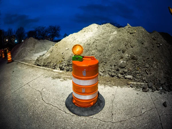 Photograph of an orange construction barrel sits in front of a large dirt pile in a parking lot near Foster beach after crews made progress on improvements to the lakefront pedestrian walking path.