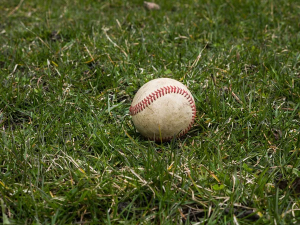 クローズ アップ スポーツ背景イメージの使用古い風化革野球ボール草フィールドを示す複雑な詳述と赤紐外に敷設 — ストック写真