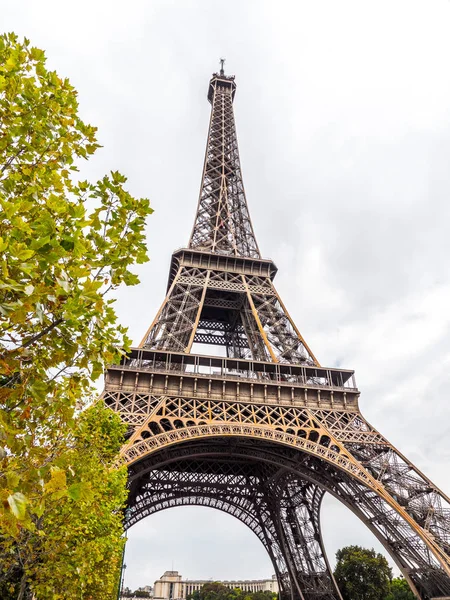 查看世界著名的埃菲尔铁塔纪念碑或地标与明亮的绿色树框架的看法和白色多云的天空超越在明亮的晴天在巴黎法国 — 图库照片