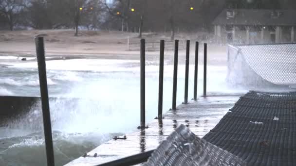 Slow Motion of large waves crash and Explode into the Tiered concrete barriers and splash on the nearby walking surface near Foster Beach on a cold windy day in the Edgewater neighborhood in Chicago . — Vídeo de Stock