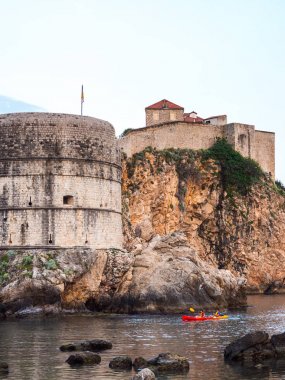 Dubrovnik, Hırvatistan - 28 Nisan 2018: Turist Adriyatik Denizi tarihi duvar şehir surları etrafında kendi kayık teknelerle kürek ve kayalık uçurum bir yukarı için güneşli bir akşam Görünümü Kapat.