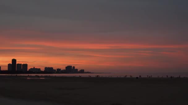 在密歇根湖畔的芝加哥海滩上 一片美丽的粉色和橙色的夕阳西下 黄昏时分 人们和建筑物的轮廓呈现在地平线上 — 图库视频影像