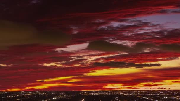 赤オレンジ ピンク 黄色の雲が地平線を照らし 飛行機や交通機関がシーン全体を移動するときに 火のようなタイプの日没に空と垂直のパンニングの街並が経過します — ストック動画