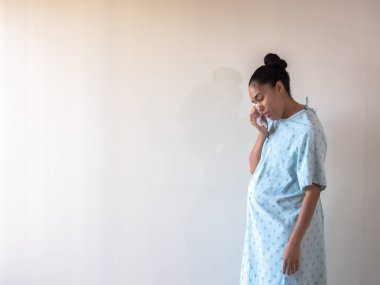 Doğum sonrası melez bir Afro-Amerikan kadın hastane önlüğü ya da cübbesi giyer. Üzüntüden ya da depresyondan gözlerini kurulamaya çalışırken eğilir..