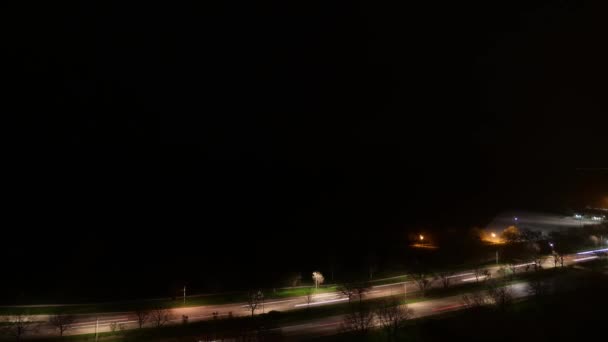 当飞机上的灯光从头顶飞过 在密西根湖上空的漆黑夜空中创造出复制空间时 夜间从湖滨道的大灯和尾灯上经过的车辆红绿灯小径的时间 — 图库视频影像