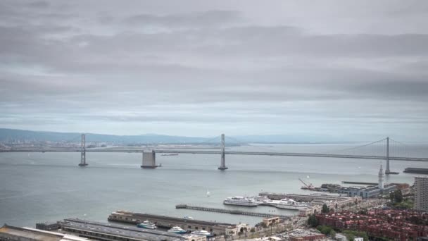 交通がエンバカデロとサンフランシスコ オークランド ベイブリッジを越えて移動すると 忙しい春の朝にサンフランシスコ湾を航行するボート フェリーの空中時間経過 — ストック動画