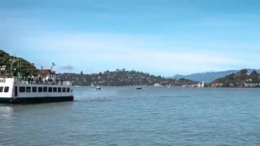 Yelkenliler San Francisco Körfezi 'nin mavi sularında Melek Adası' ndaki Yalnız Noktası 'nın yakınından geçiyor. Güneşli, güneşli bir ilkbahar mavi gökyüzü günü. Gökyüzünde Tiburon ve Belvedere ufuk çizgisinde..