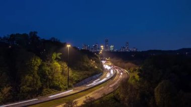 Uzun bir zaman aralığı ışık yolları ve kavisli bir yoldaki trafik geceleyin Toronto şehir merkezine uzanan ağaçların yol kenarlarında çizdiği siluet..